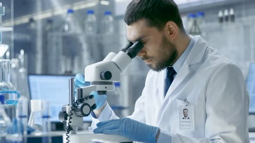 Focused Scientist Using Microscope in Bright Modern Lab