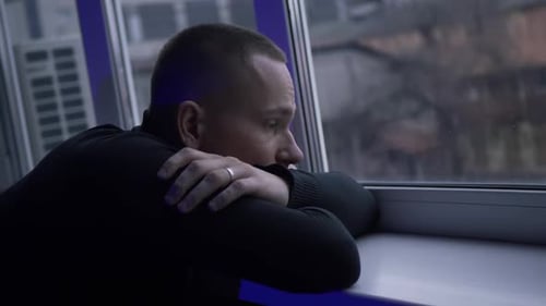 Pensive Man Gazing Out City Window