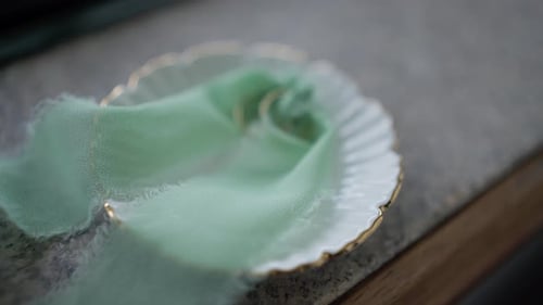 gold wedding rings tied with silk ribbon on ceramic dish