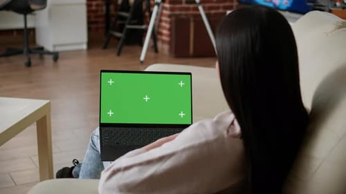 Woman Sitting on Sofa at Home While Looking at Laptop Having Green Screen