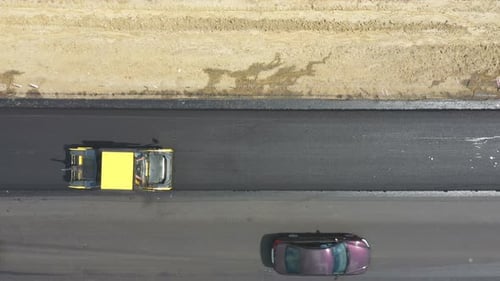 Aerial Shot of Roller Laying New Asphalt Layer and Cars Passing By Top View to Special Machinery