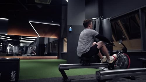 Man Using Rowing Machine in Gym