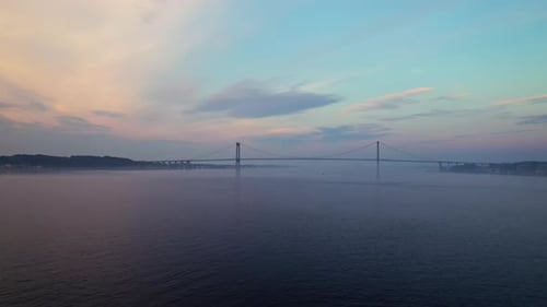 Drone over sea at dusk towards bridge