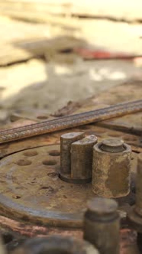 Slow motion close up of worker bending rebar with industrial bending machine at construction site
