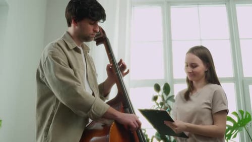 Man Plays Upright Bass While Woman Takes Notes