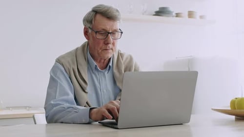 Senior Man Using Laptop Computer at Home