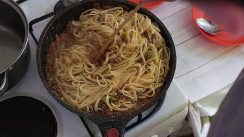Spaghetti being stirred in a frying pan