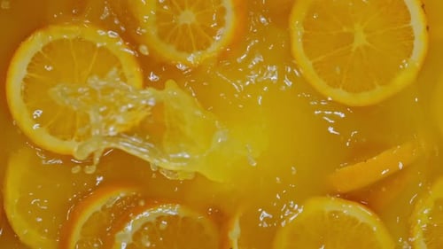 Orange Slices Falling Into a Pool of Juice