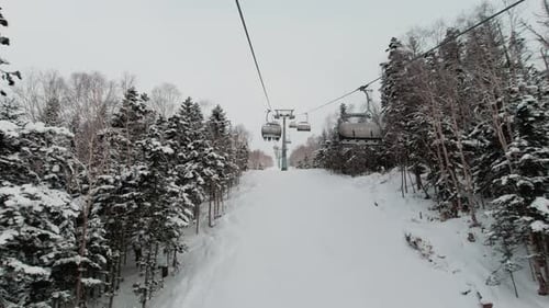 Riding on Ski Lift Above the Slopes Between Snow Covered Pinetrees POV Shot Winter Vacation Concept