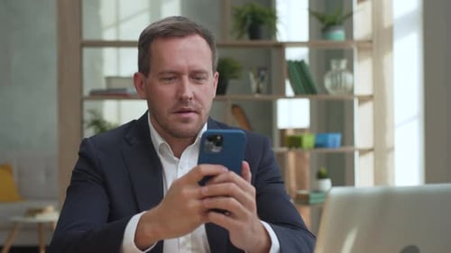 Man in Suit Reacts to Phone Positively