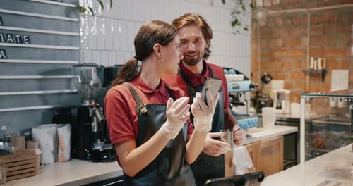 Baristas Looking at a Cellphone in Coffee Shop
