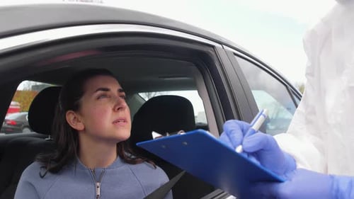 Doctor in protective gear doing coronavirus test at drive through mobile clinic