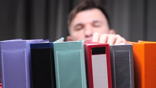 A Man Puts a Folder with Documents on a Shelf Archive of Documents