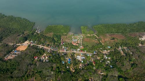 Aerial view of coastal village in Koh Yao Yai island surrounded by verdant forest and blue ocean