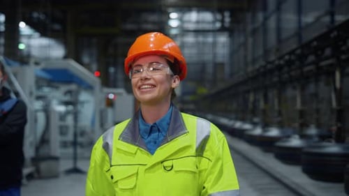 Joyful supervisor woman laughing in safety uniform at modern warehouse facility