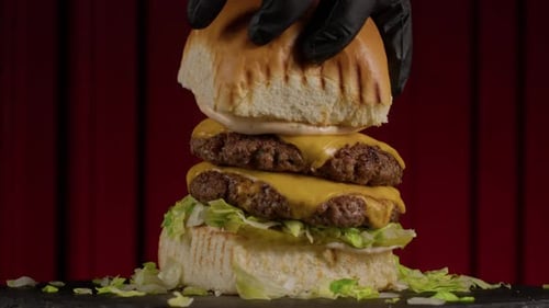 Der Koch legt ein Brötchen mit geschmolzenem Käse auf einen Burger