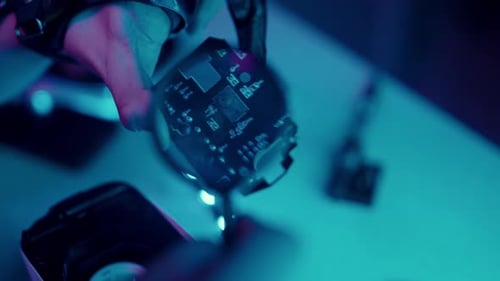 Hand Holding Circuit Board in Neon Lit Environment