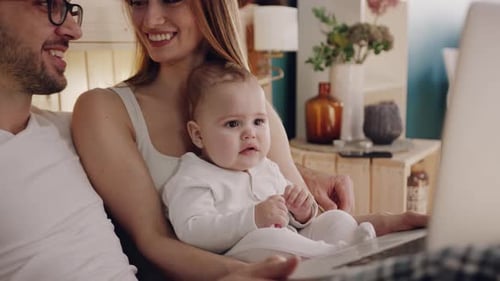Young Family Using Laptop in Cozy Bedroom