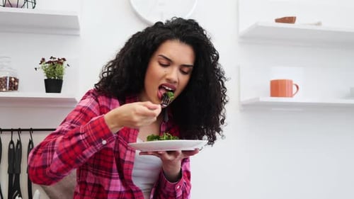 Woman Enjoys Eating Salad in a Modern Kitchen
