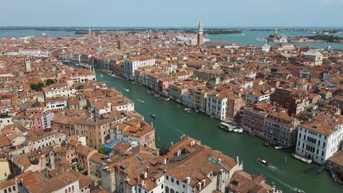 Wide aerial shot overlooking a canal with boats in Venice Italy under clear blue skies