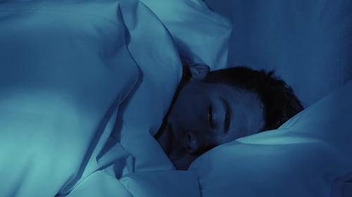 Young Adult Sleeping Peacefully in a Blue Lit Room