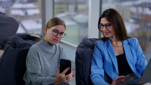 Women Collaborate on Laptop and Cell Phone in Office