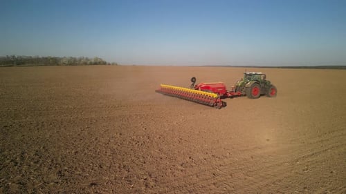 Green tractor works on the field sowing sunflower. Tractor planting corn in Ukraine