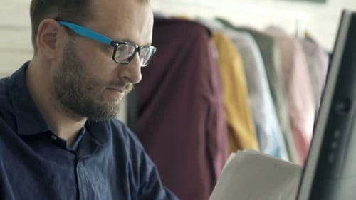Man reviews documents at a computer indoors