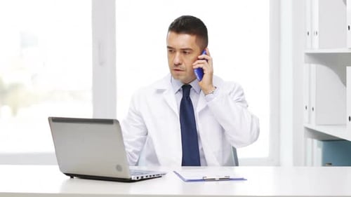 Doctor Talking on Phone, Working at Laptop