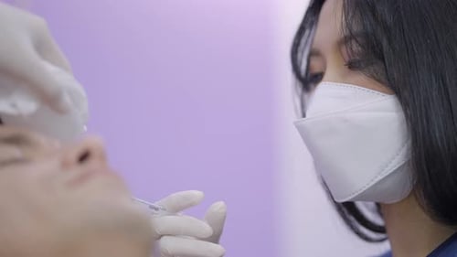 Asian Doctor Working at Plastic Surgery Clinic Performing Botox Treatment on Patient