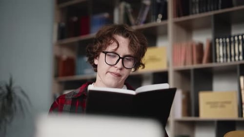 Young student reading interesting book in library