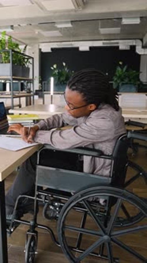 Focused Student in Wheelchair Writing During Exam Prep