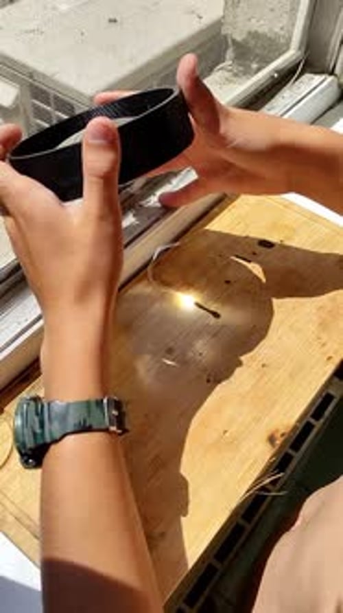 Hands Focusing Sunlight Through a Magnifying Glass to Ignite a Small Object on a Wooden Surface