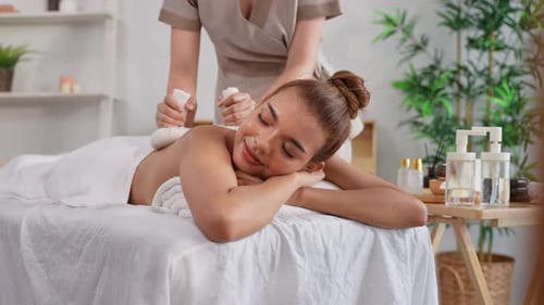 Beautiful woman getting thai hot compress massage with herbal bags.