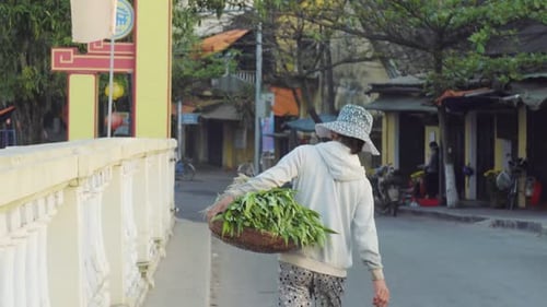 Early morning market vendor heads to the market stall in the traditional city of Hoi An in Vietnam