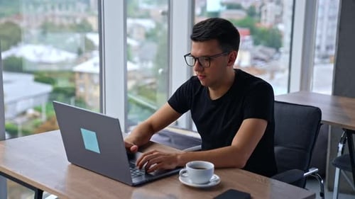 Young Adult Working on Laptop in Modern Office