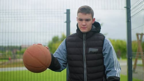 Young Man Dribbling Basketball on an Outdoor Court