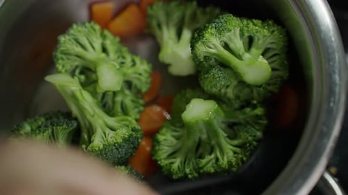 Fresh Broccoli and Carrots Being Mixed in Pot