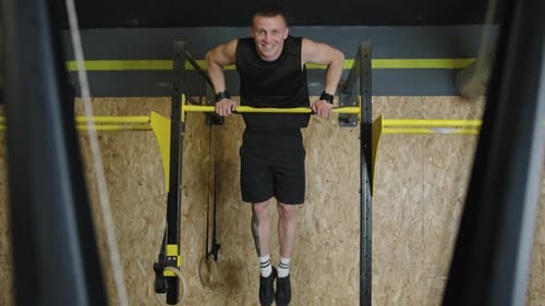 Strong man performs muscle ups in slow motion at the gym showcasing strength and determination