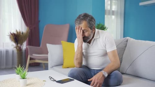 Middle Aged Man Examining Ring on Couch at Home
