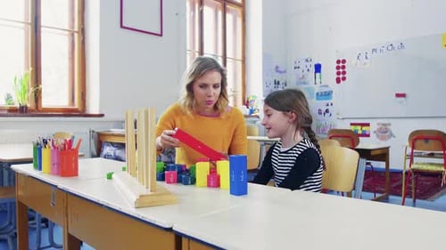 Young girl learns fractions from teacher in bright elementary school classroom