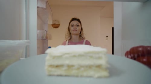 Woman takes cake out of refrigerator