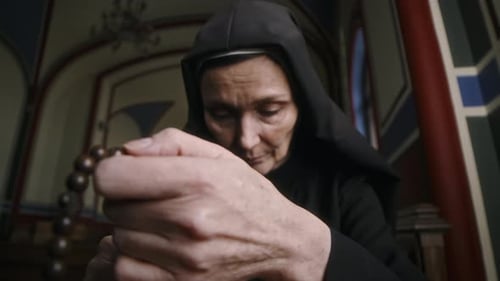 Senior Person Praying in Church with Rosary