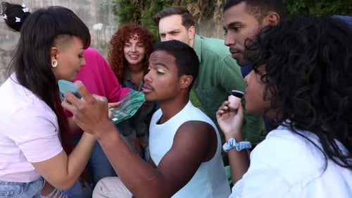 Friends applying make up on non binary person outdoors
