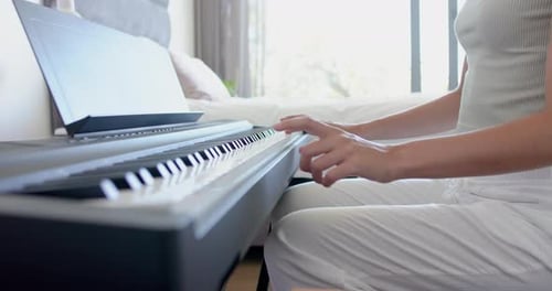 A teenage caucasian girl is playing a digital piano, learning a piece