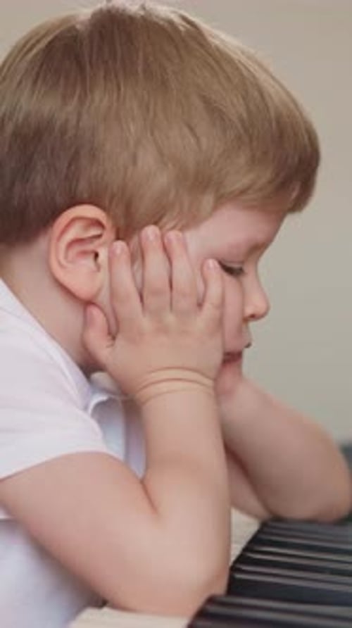 Little Boy Stops Playing Piano and Puts Elbows on Keyboard