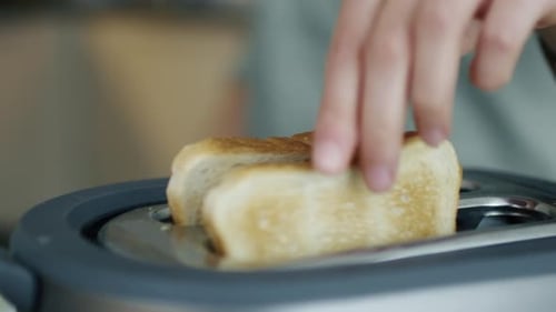 Close-up of a Woman Taking Toasts out of a Toaster.