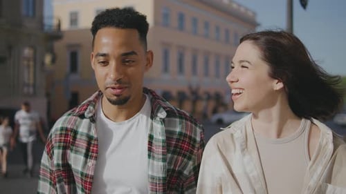 Multiethnic Couple in Love Walks Along the Streets of a European City The Guy and the Girl are Happy