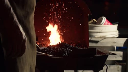 Glowing fire and sparks in blacksmith forge at night