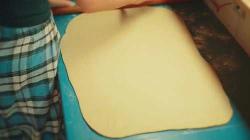 Teig für hausgemachte Zimtschnecken ausrollen, Nahaufnahme eines Teenagers beim Backen.